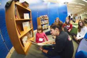 Helen Sharma SSH'17 reads a book from the Favat collection to a young guest.