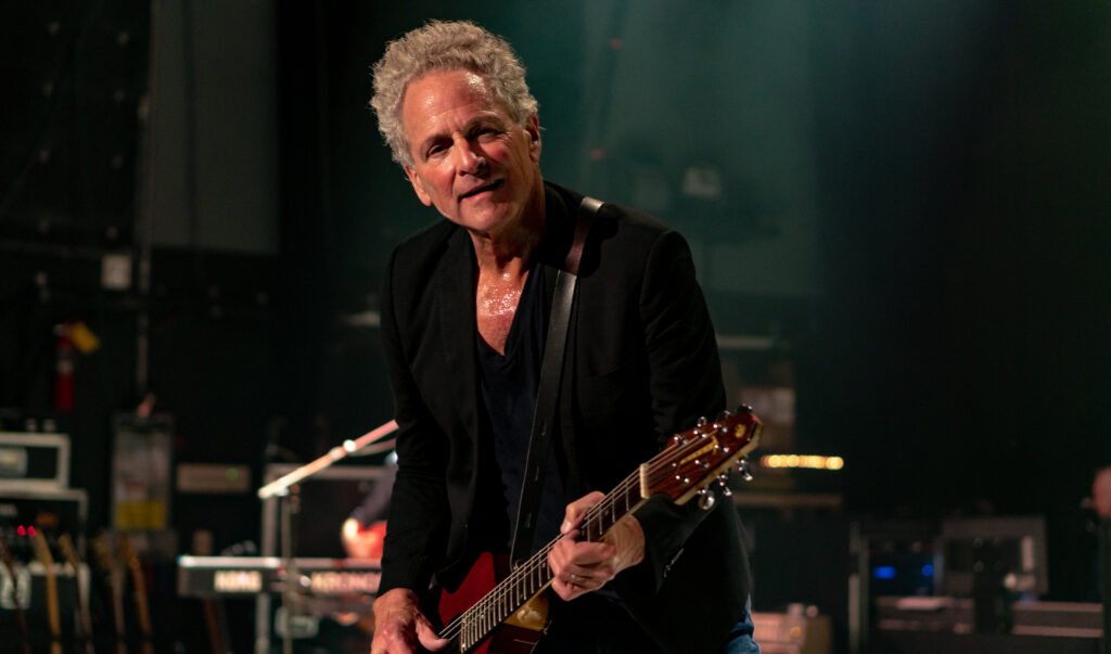 Lindsey Buckingham plays guitar on a stage