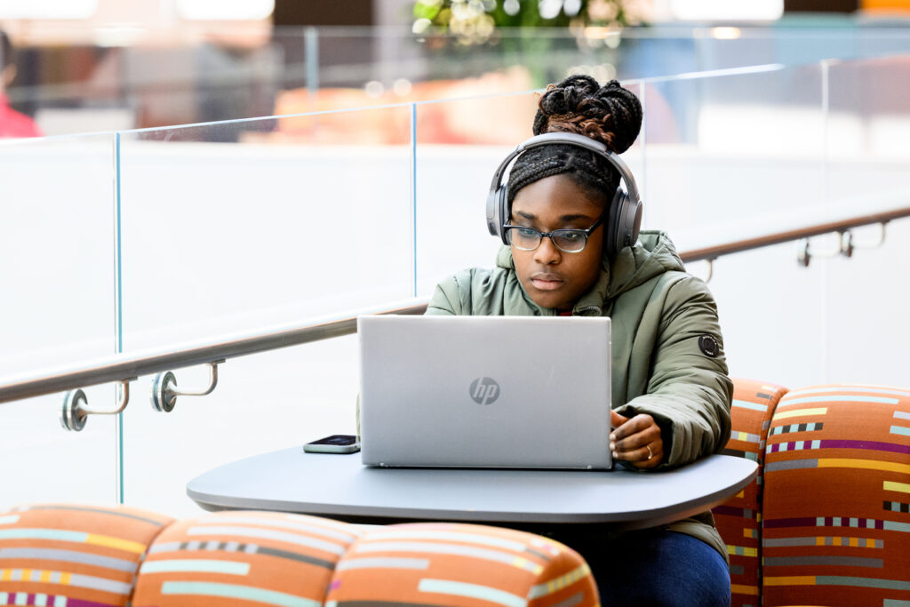 A student sits behind a laptop wearing headphones on the newly renovated 4th floor of Snell Library