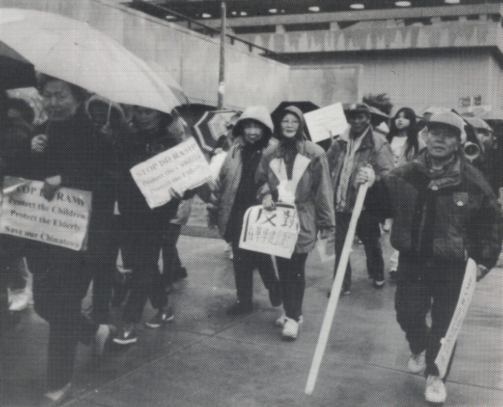 Black and white image of people marching and holding signs