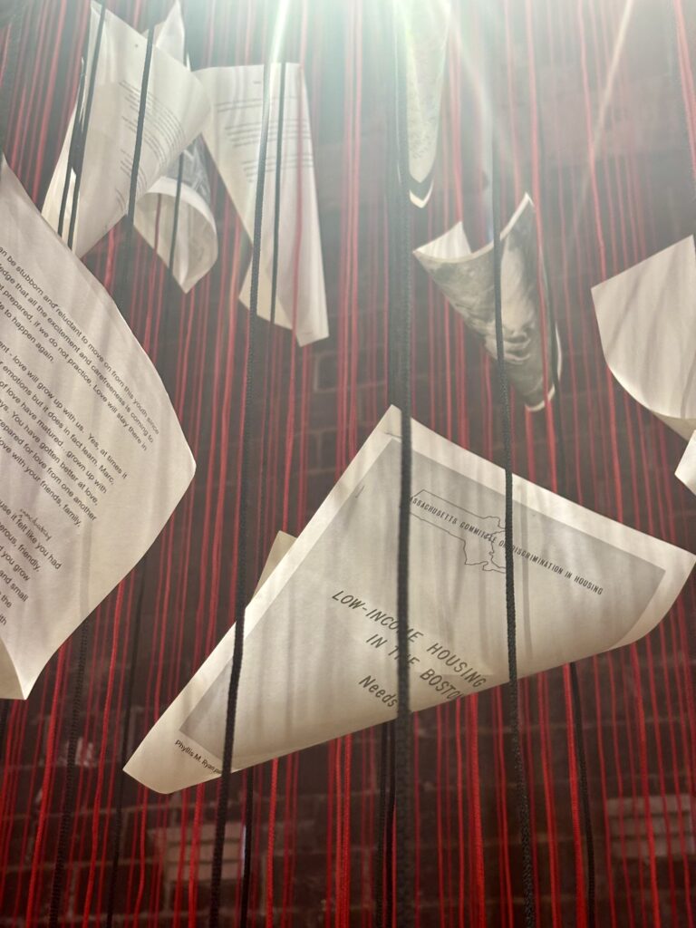 Papers suspended within hanging red threads